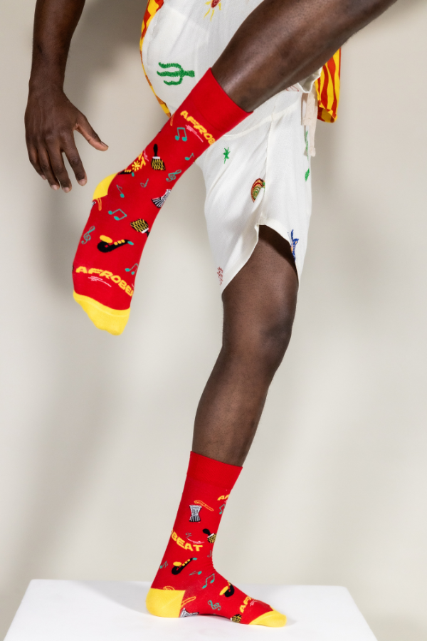 Red socks. Afrobeat socks is a celebration of Afrobeat. The West African music genre was pioneered in the 1960s by Nigerian artist, Fela Kuti. It is a mixture of traditional Yoruba music such as fuji and other contemporary sounds of the time, like jazz and soul.

Instruments on socks: shekere, djembe drum, talking drum, saxophone